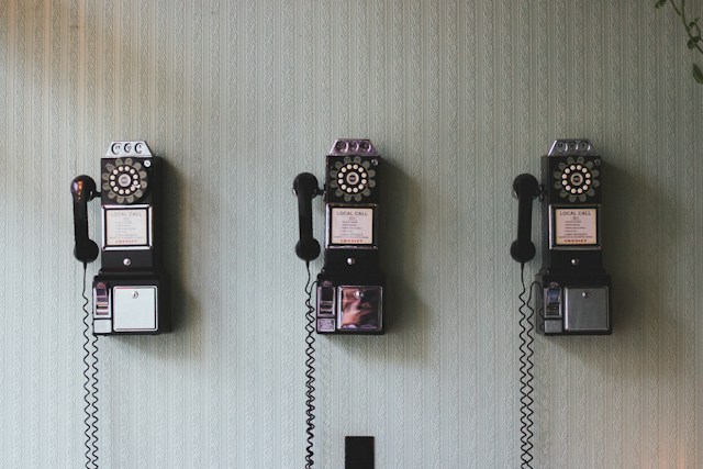 três telefones manivela em uma parede